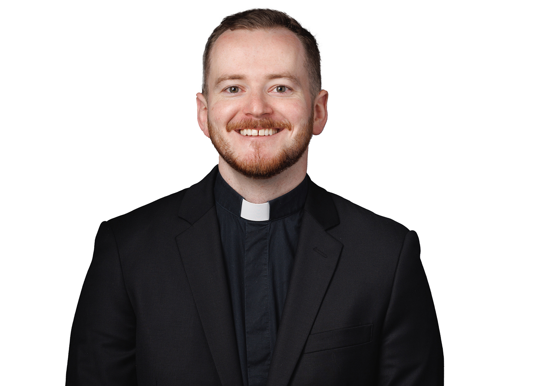 Headshot of a man wearing a clerical collar and black jacket, smiling against a light background